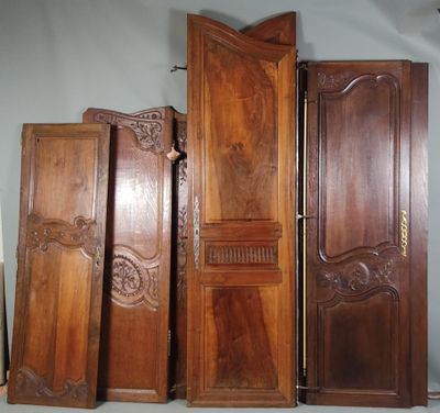 Plusieurs portes en bois sont alignées contre un mur dans une pièce