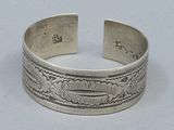 silver cuff bracelet with a design of waves and clouds on it