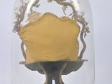 a yellow cake in a glass dome on a stand