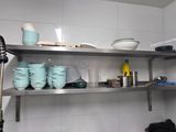 a metal shelf with dishes and cups on it in a kitchen