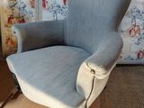 a blue chair that is sitting in front of a wallpapered wall