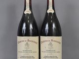 two bottles of red wine sitting on top of a table