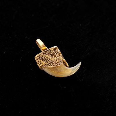 a close up of a gold pendant on a black surface