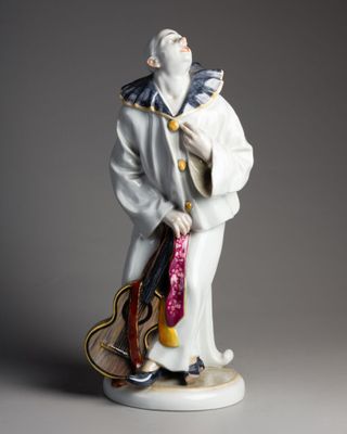 une vieille figurine représentant un homme avec une guitare, posée sur une table