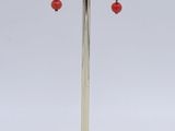 earrings with red beads on a stand on a white background