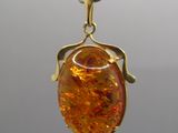 an image of a gold colored pendant with a large orange stone