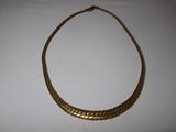 a close up of a gold necklace on a white surface
