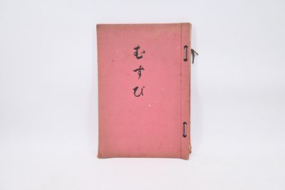 un vieux livre rose, orné d'inscriptions en chinois, posé sur une surface blanche