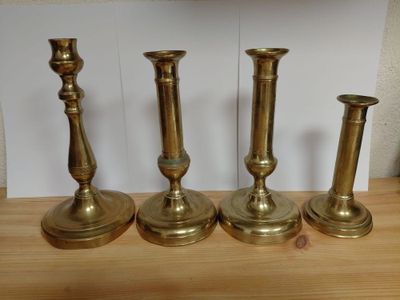 four brass candlesticks sitting on a wooden table
