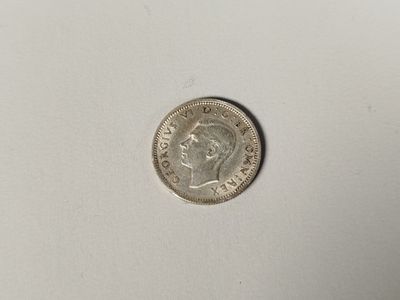 a silver coin on a white surface with a white background