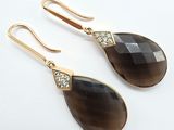 une paire de boucles d'oreilles noires et dorées ornées de cristaux