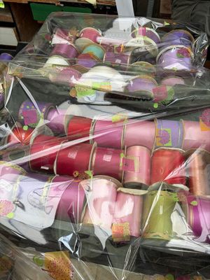many rolls of fabric wrapped in plastic bags on a table