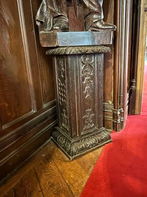 une statue représentant un homme debout derrière un pupitre dans une pièce