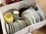 a box full of plates and cups sitting on a table