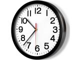 une horloge noire avec des chiffres blancs, accrochée à un mur blanc