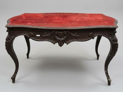 une vieille table avec un plateau en velours rouge et des pieds ouvragés