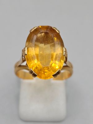 un gros plan d'une bague sertie d'un saphir jaune sur une surface blanche