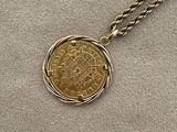 a close up of a gold coin on a gold chain