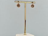 une paire de boucles d'oreilles posée sur un présentoir, sur une surface en marbre