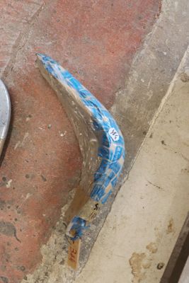 un siège de WC cassé, posé par terre à côté d'un mur de briques