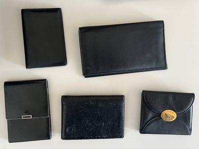 four black leather wallets and a cell phone sitting on a table