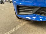a close up of a blue car parked in a parking lot