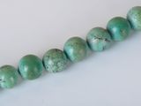a close up of a strand of turquoise green beads on a white surface