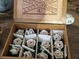 a box of roses sitting on a table next to a teapot