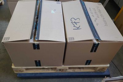 trois cartons posés sur une palette dans un entrepôt