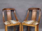 deux chaises en bois dont les assises sont ornées d'un motif léopard, posées contre un mur gris