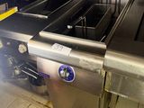 someone is standing in a kitchen with a fryer in the middle of the floor