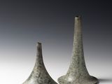 une paire de vases gris posés sur une surface blanche