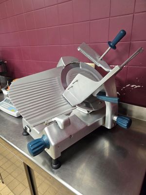 stainless steel counter top with a meat slicer on top of it