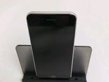 a black cell phone sitting on a stand on a white surface