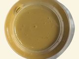 mustard sauce in a bowl on a white surface