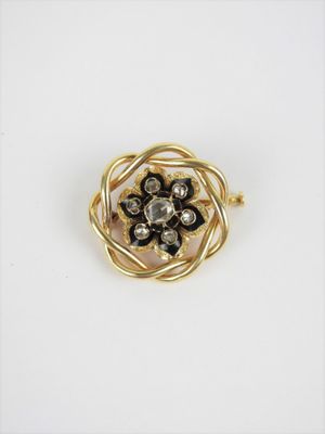 un gros plan sur une broche en forme de fleur dorée et noire