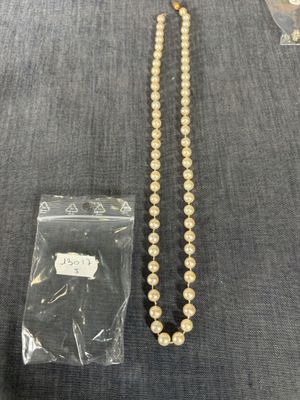 un gros plan d'un collier de perles posé sur une table à côté d'un sac en plastique
