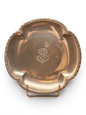 an antique silver plate with a flower design on the rim