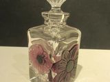 a clear glass bottle with a flower design on it