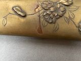 a gold vase with flowers on it sitting on a table