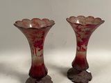 une paire de vases en verre rouge posés sur une table blanche