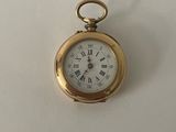 une petite montre de poche en or avec des chiffres romains