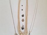 plusieurs colliers et bracelets différents posés sur un fond blanc