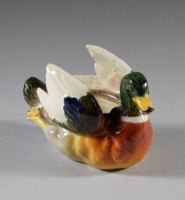 un petit canard en céramique posé sur un bol