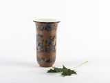 un petit vase avec une feuille par terre