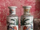 two vases sitting on a table in front of a wall