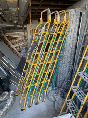 Des échelles jaunes sont empilées les unes sur les autres dans un garage.