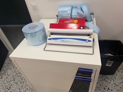 a white desk with a printer and a roll of toilet paper on it