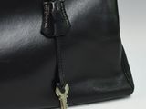 black leather handbag with a key in the middle of it