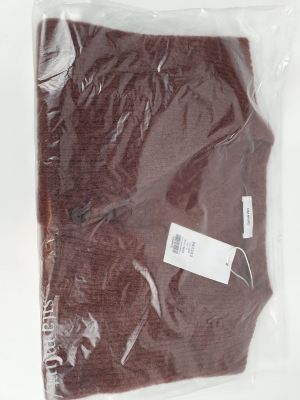 une chemise marron dans un sac en plastique posé sur une surface blanche
